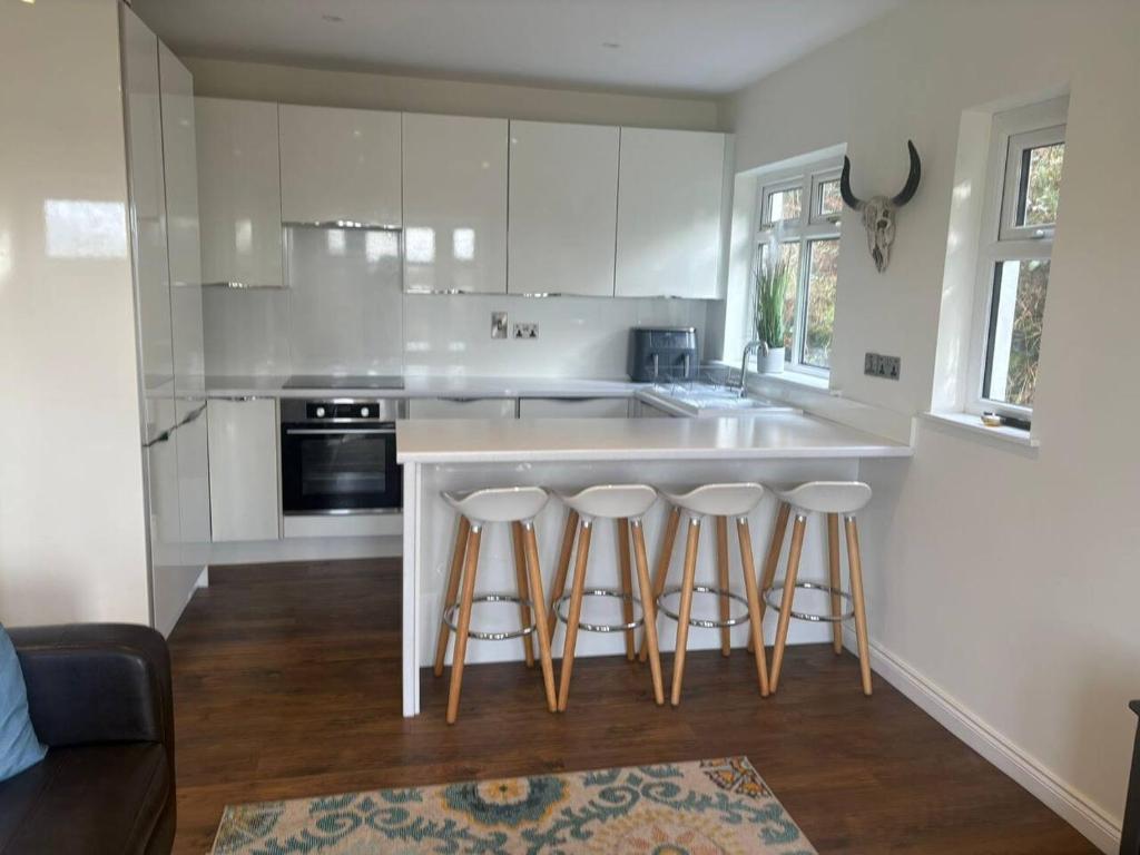 a kitchen with white cabinets and a counter with bar stools at Stylish Holiday Home - Caherdaniel in Caherdaniel