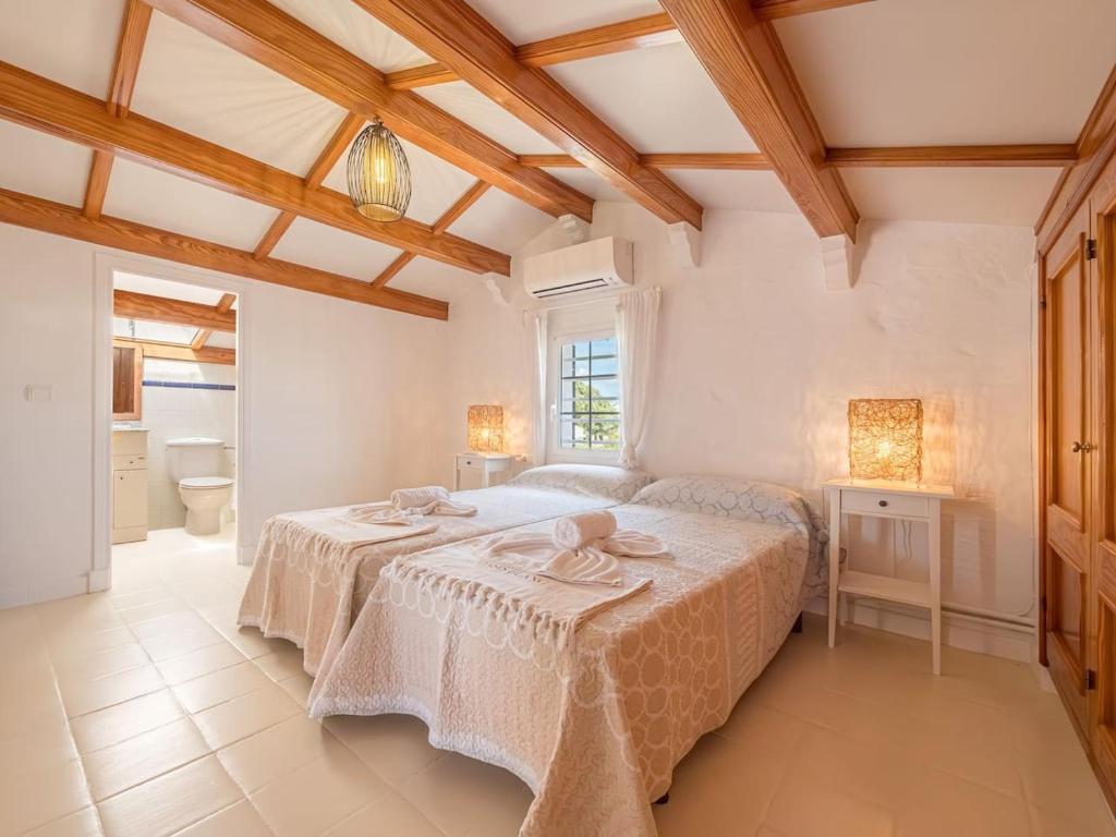 a white bedroom with a bed and a bathroom at Can Borras by 3VILLAS in Llumesanas