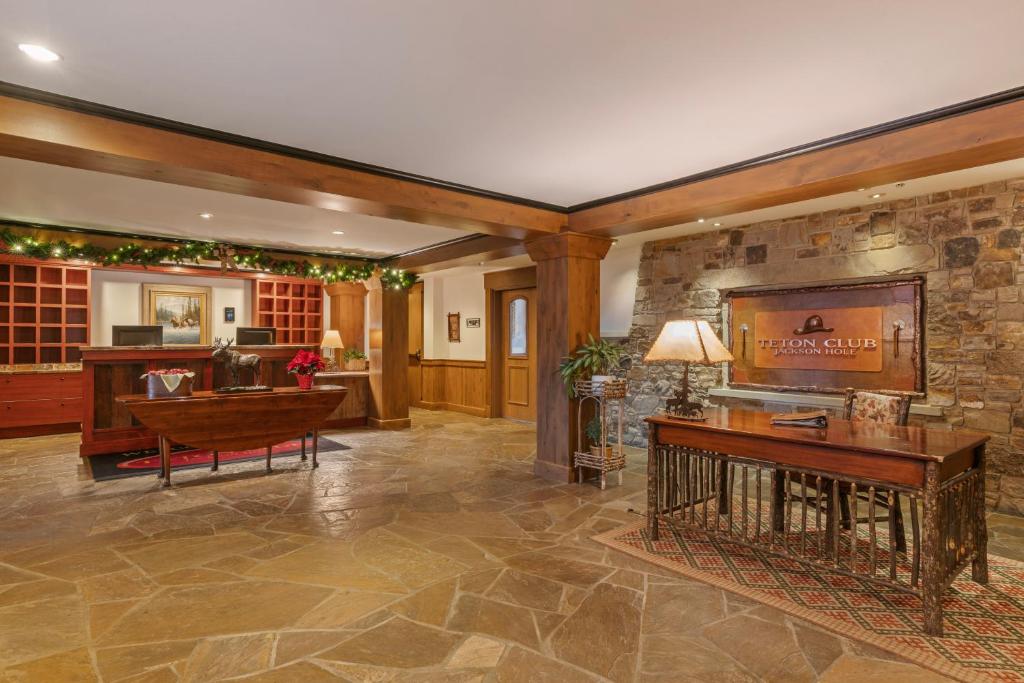 a lobby with a wooden table and a stone wall at Teton Club in Teton Village