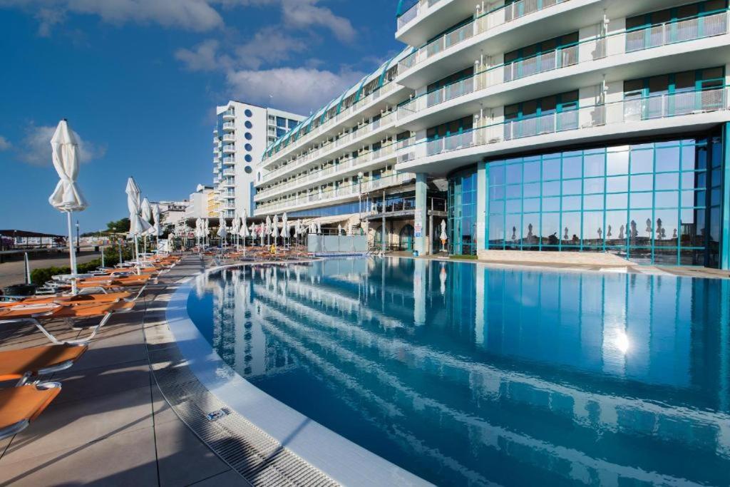 a hotel with a swimming pool in front of a building at Berlin Golden Beach Studio in Varna City