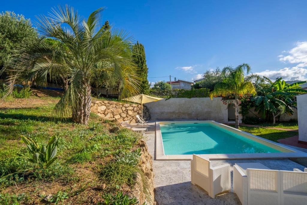 a swimming pool in a yard with palm trees at CAPOVILLAS - Villa Laura with private pool in Vibo Valentia
