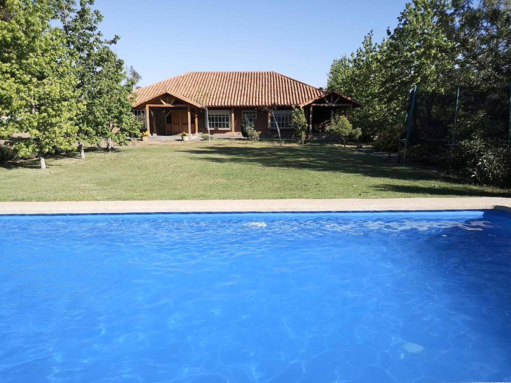 a large blue swimming pool in front of a house at Casa de Campo, tranquilidad natural in Curicó
