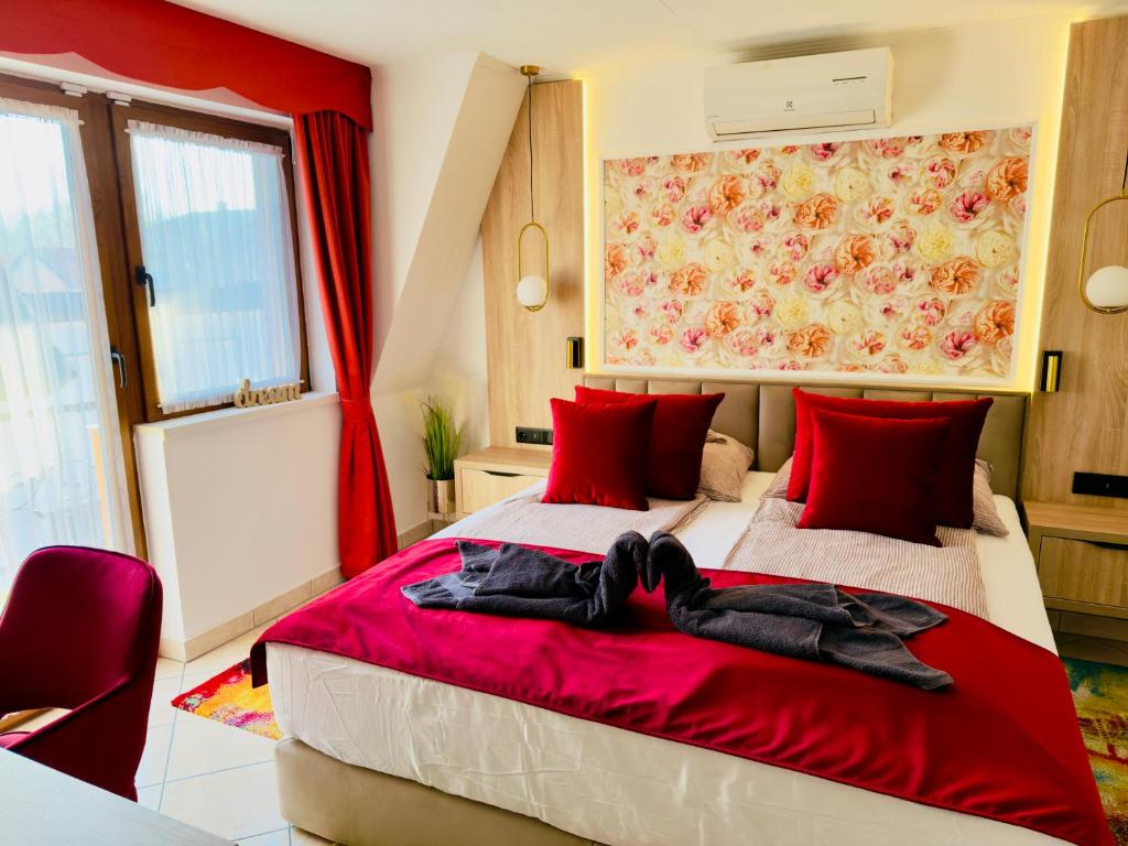 a bedroom with a large bed with red pillows at Villa Peonia-Szauna & Relax in Keszthely