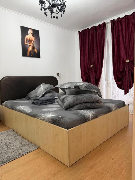 a large bed in a bedroom with red curtains at Afrodita Apartment in Timişoara
