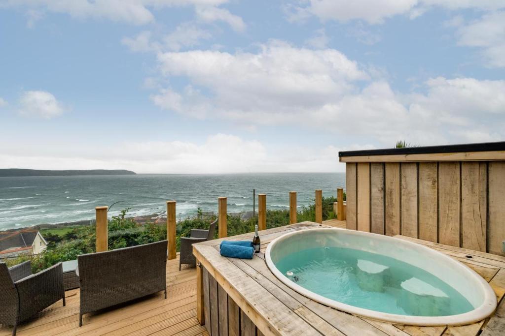 a hot tub on a deck with a view of the ocean at 5 Bed in Woolacombe oc-alba12 in Woolacombe