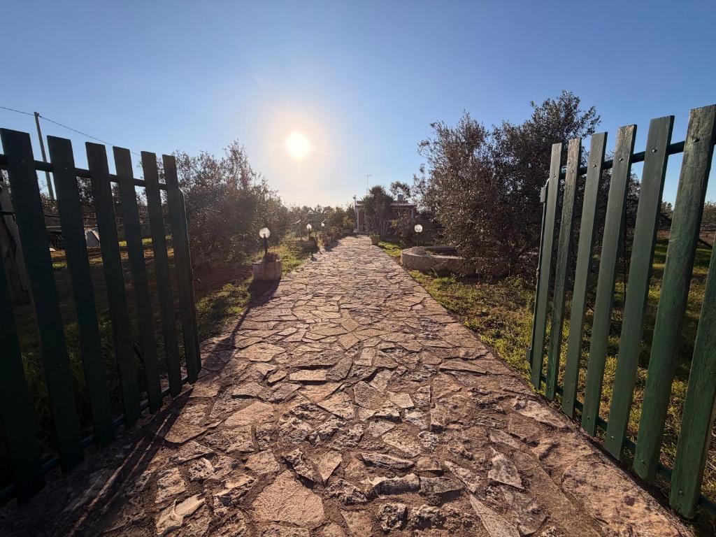a stone path with a fence and the sun in the sky at Villa Flora Gallipoli in Il Monte