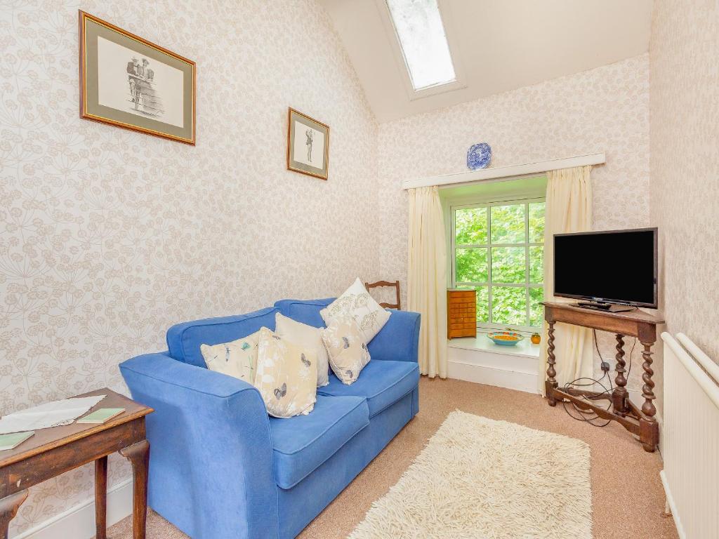 a blue couch in a living room with a tv at The Cottage in Slickly