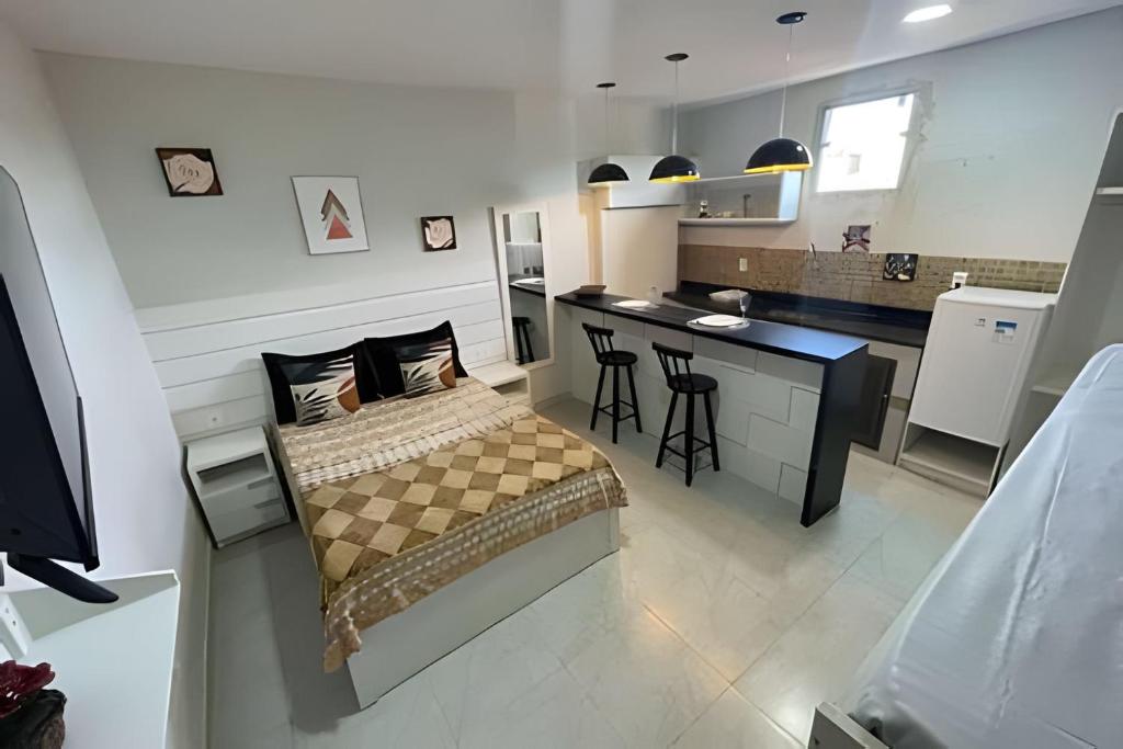 a small bedroom with a bed and a kitchen at Central Praias Suíte 202 com ar, tv, frigobar, banheiro privativo, espaçosa em frente à praça in Cabo Frio