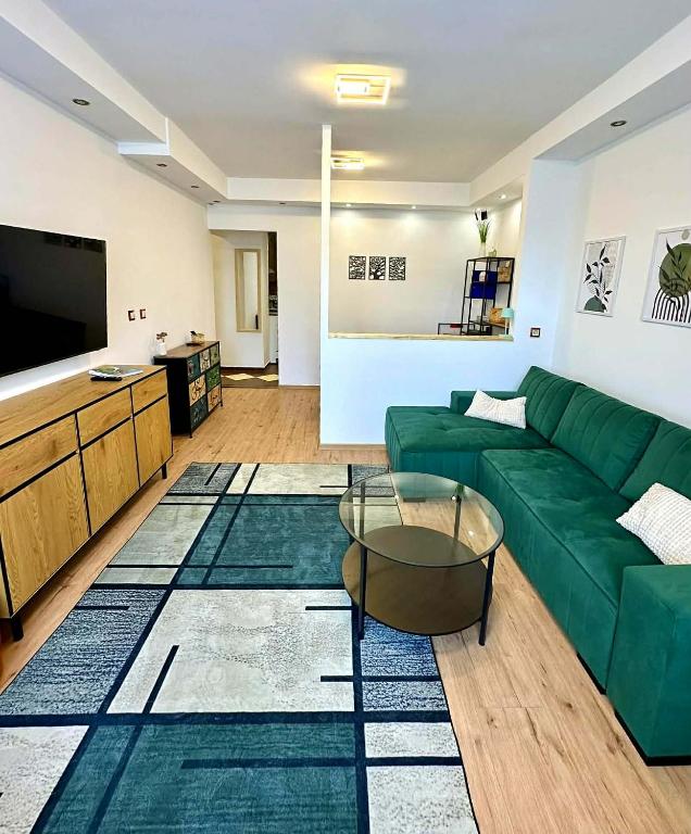 a living room with a green couch and a flat screen tv at VestaLak in Tata