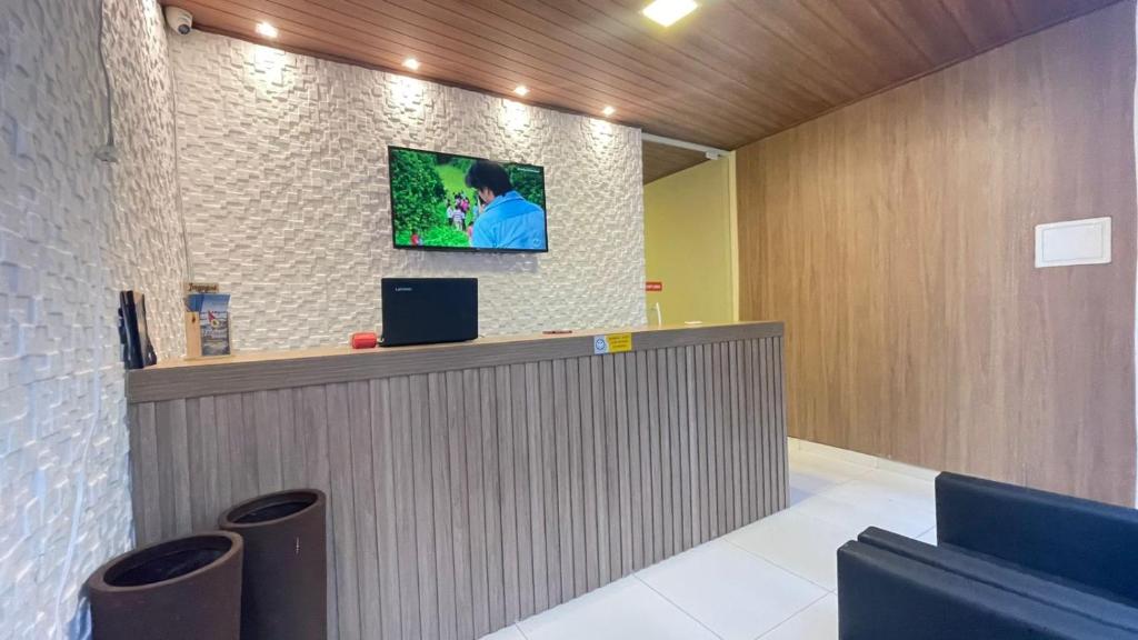 a lobby with a counter with a tv on the wall at Pousada Corais de Pajuçara- MCZ in Maceió