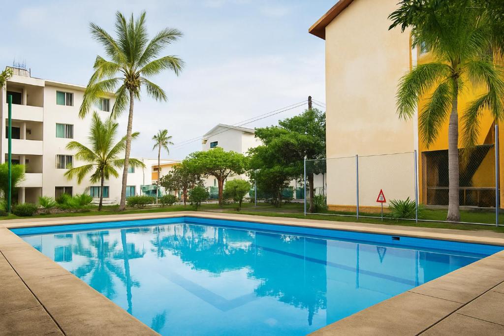 a swimming pool in front of a building with palm trees at condominio los mangos in Santa Cruz Huatulco