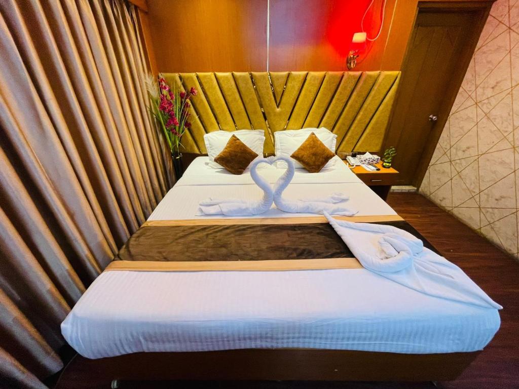a hotel room with two beds with a swan on them at Hotel Rosewood Uttara in Kāmarpāra