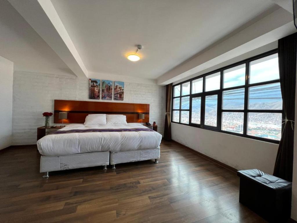 a bedroom with a large bed and large windows at La Estancia del Abuelo in Cusco