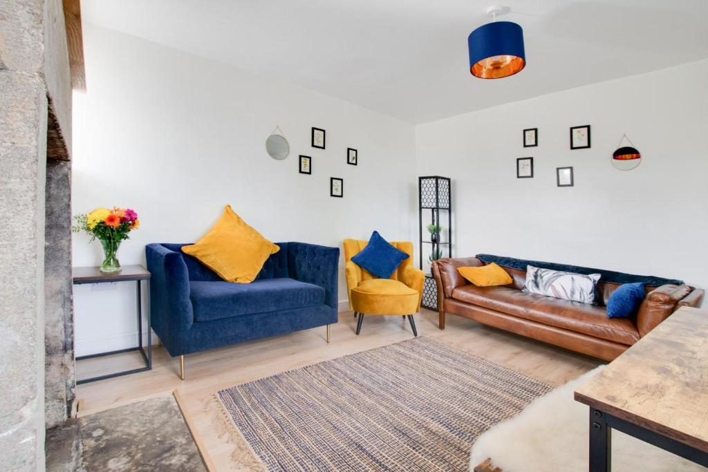 a living room with two blue couches and yellow pillows at 2 Bed in Matlock oc-dcbeau in Crich