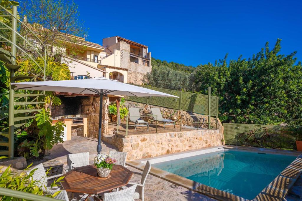 a patio with a table and an umbrella next to a pool at Es Raco in Caimari