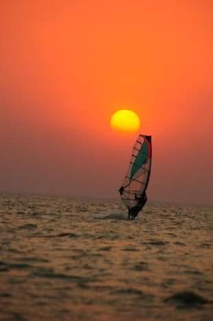 a person is windsurfing in the ocean at sunset at Complejo El Teyu in Miramar