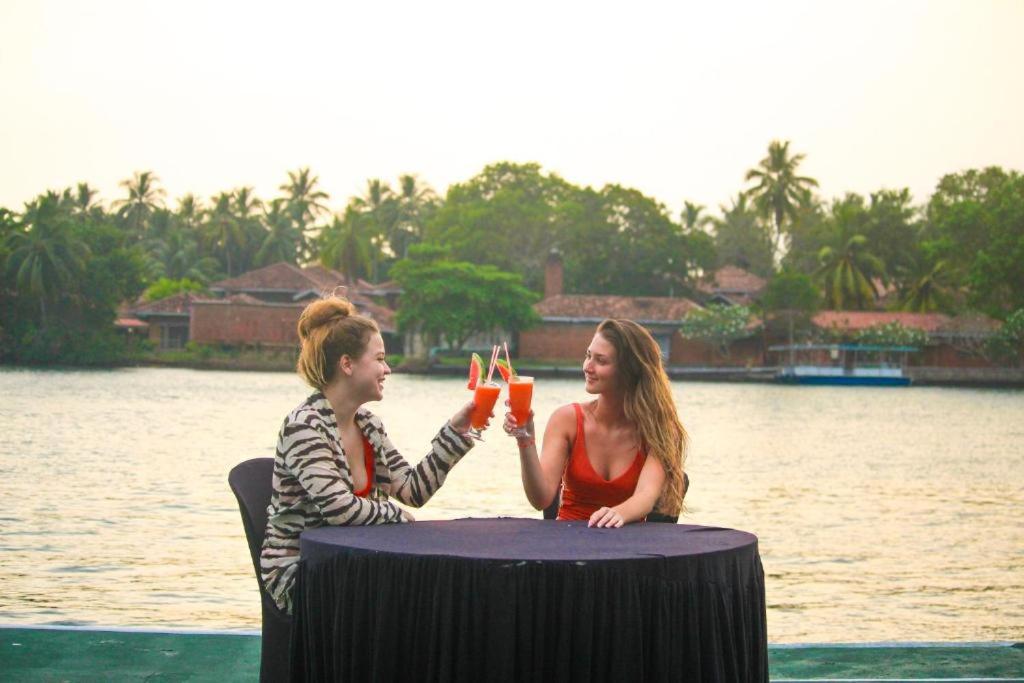 two women sitting at a table drinking orange juice at Sunset Araliya by Diyakawa in Aluthgama