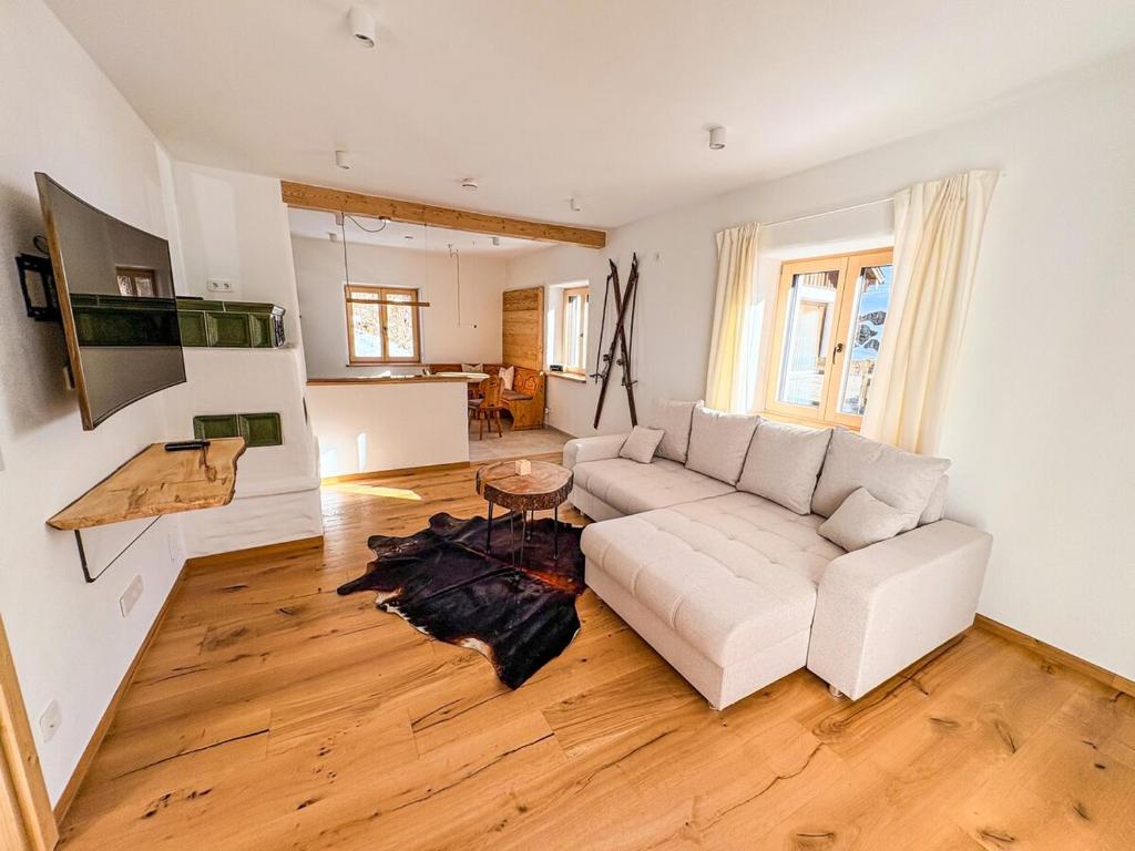 a living room with a white couch and a table at Alpenchalet Wasserfallblick in Ramsau