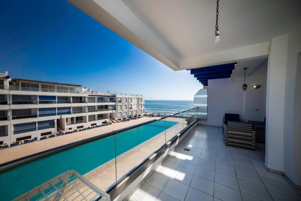 a balcony with a swimming pool and a view of the ocean at Apartment in Adan Beach Residence With Pool in Aourir