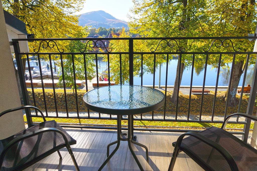 a table and chairs on a balcony with a view of the water at Nad Stawem in Ustroń