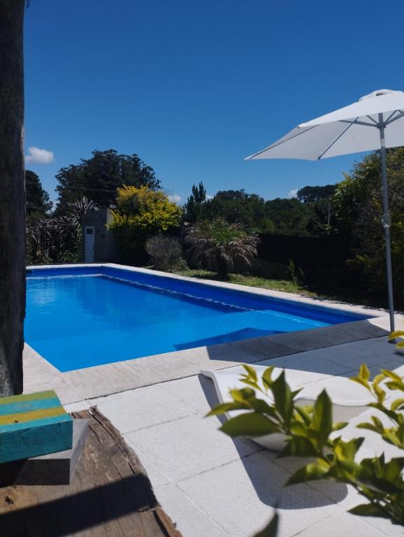 a blue swimming pool with an umbrella next to it at ParaisolaRinconada in La Porteña
