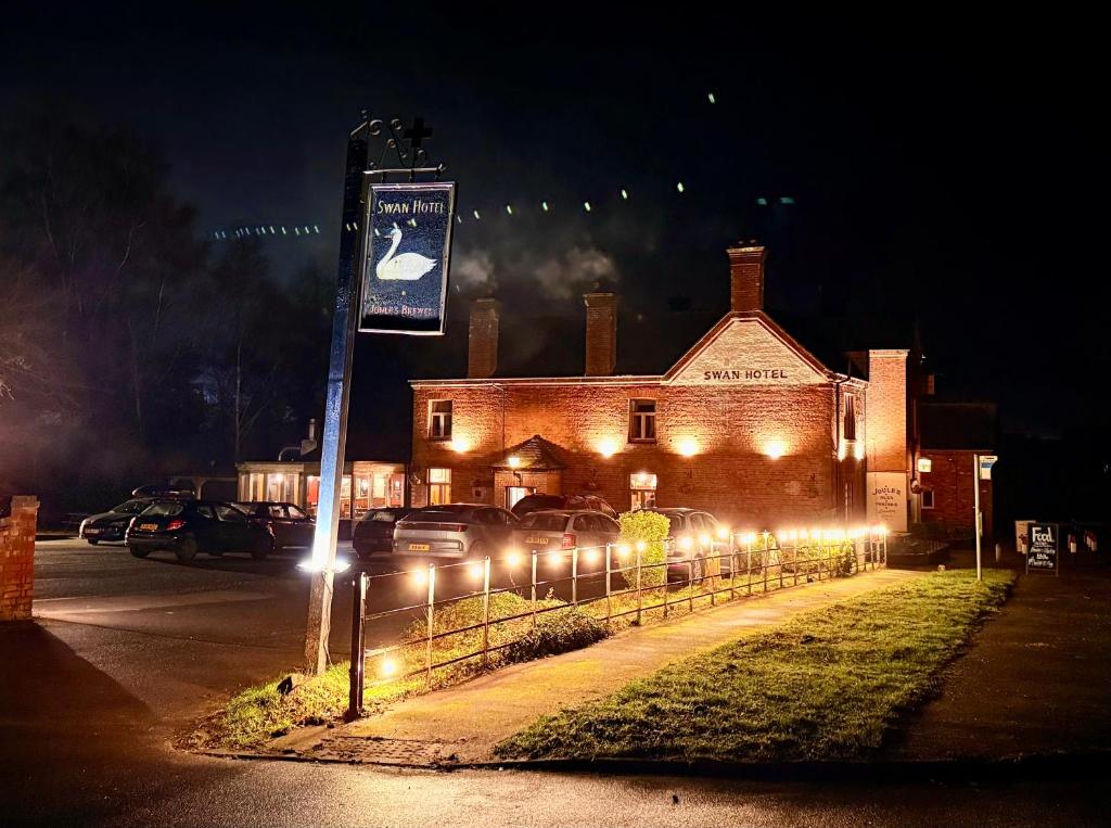 a building with cars parked in front of it at night at Swan Hotel Forton in Forton