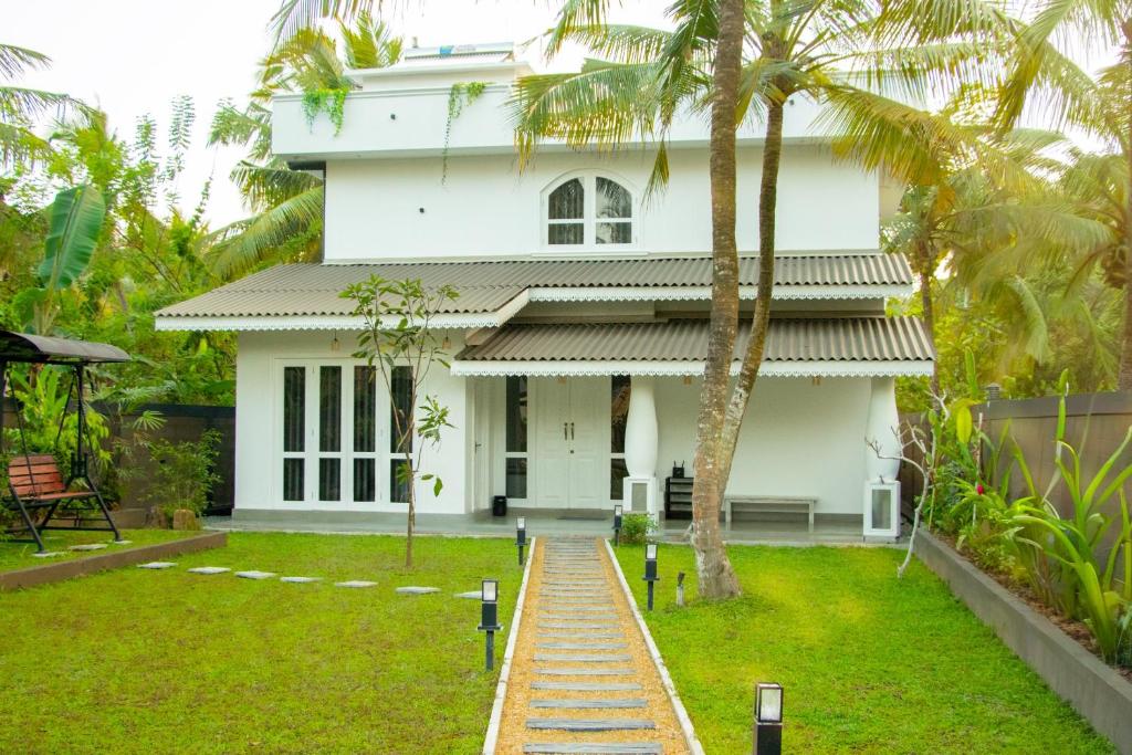 a white house with palm trees in front of it at Villa Mario in Unawatuna