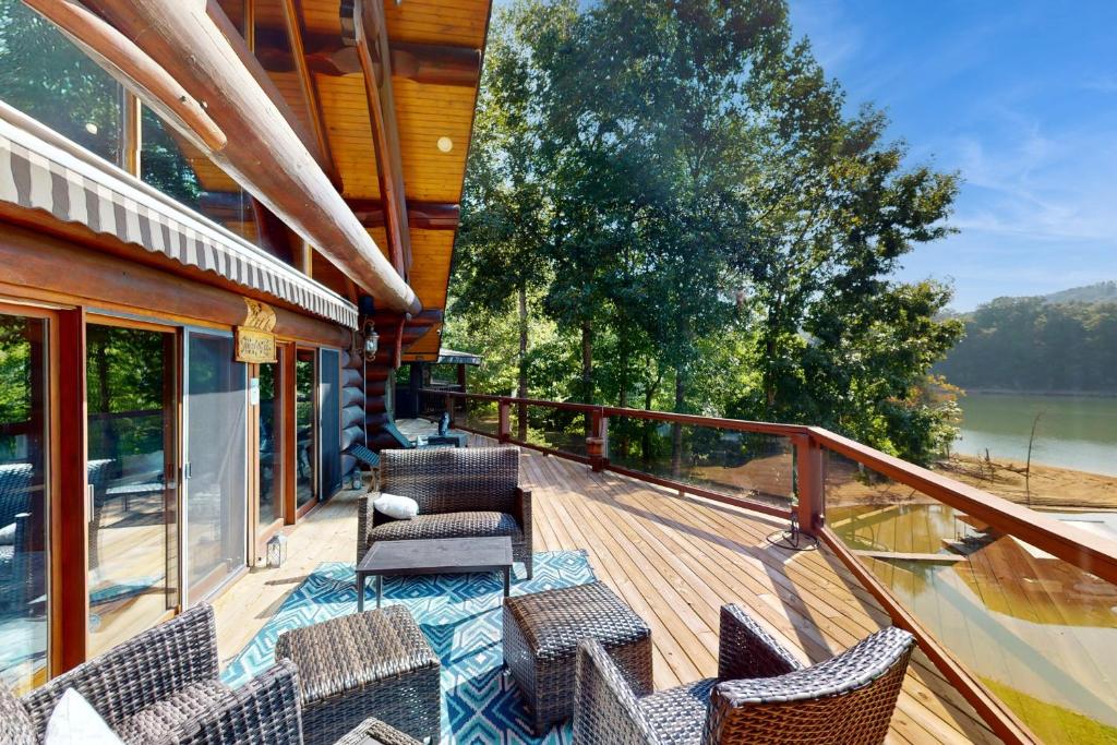 a deck with chairs and tables on a house at Hot Tub + Dock! Waterfront Norris Lake Log Home in Elm Springs