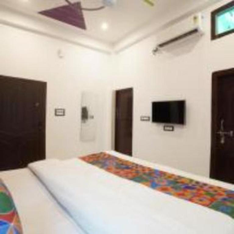 a bedroom with a bed and a tv on the wall at Jai Shree Ram hotel in Ayodhya