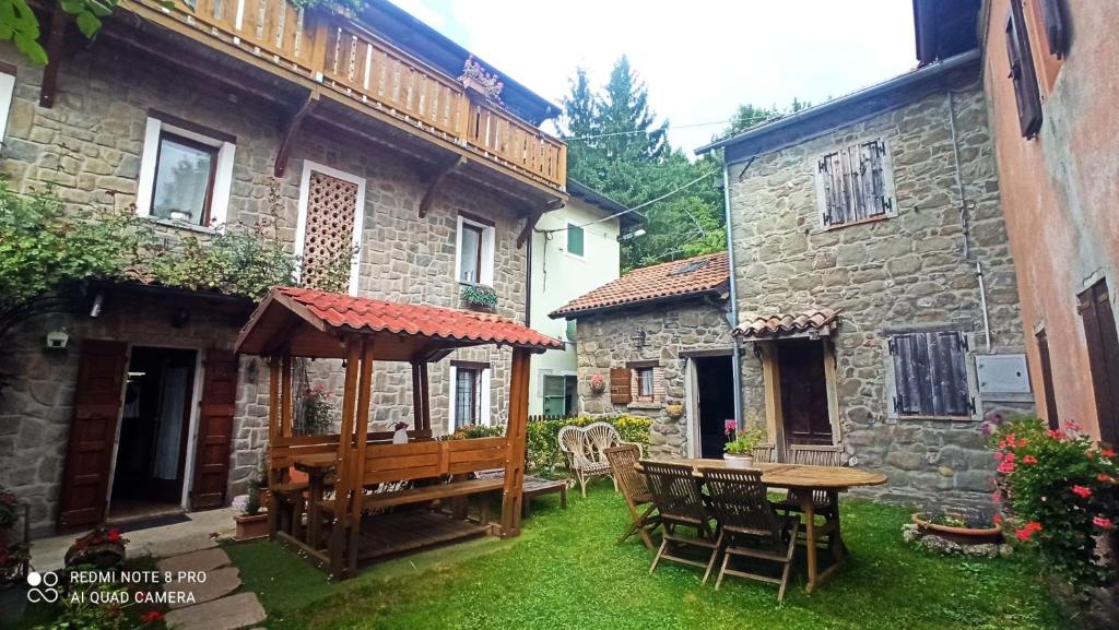 a patio with a wooden table and chairs in a yard at Il BORGO DEL VENTASSO in Busana