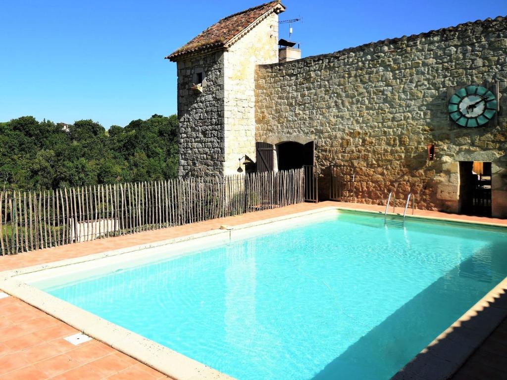 a swimming pool in front of a building with a clock at Castle near Agen with Shared Pool in Saint-Caprais-de-Lerm