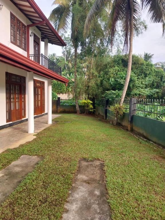 a yard in front of a house with a fence at Villa Anu in Hikkaduwa