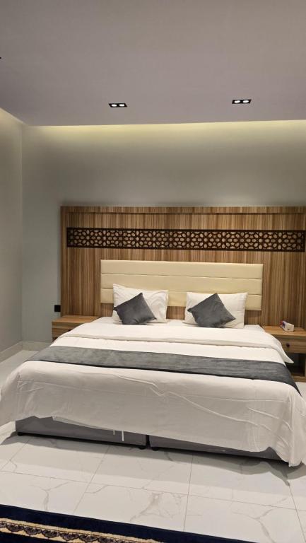 a bedroom with a large bed with a wooden headboard at شقق الدار in Jeddah