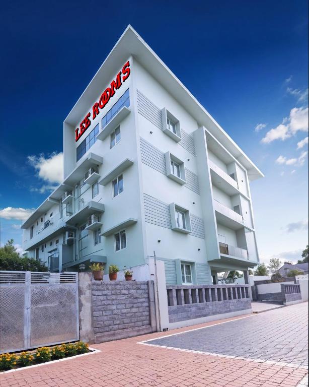 a large white building with a red sign on it at Lee Rooms in Nāgercoil