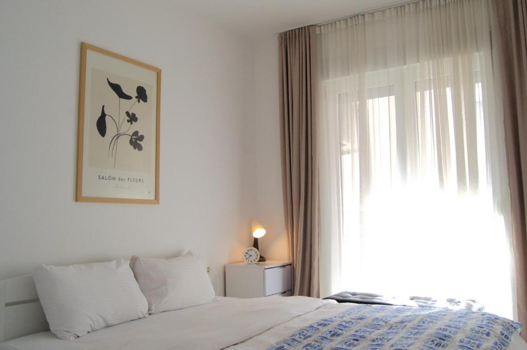 a white bedroom with a bed and a window at Yeshill Deluxe Apartment in Budva