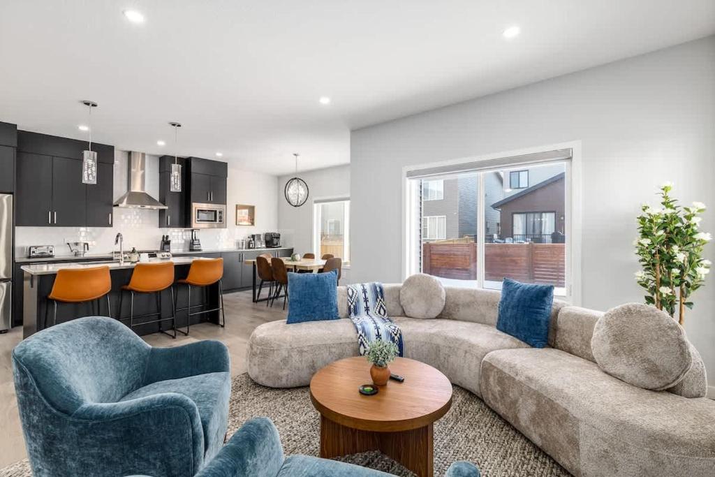 a living room with a couch and chairs and a kitchen at Arcade King Bed Espresso Maker Family Friendly in Airdrie