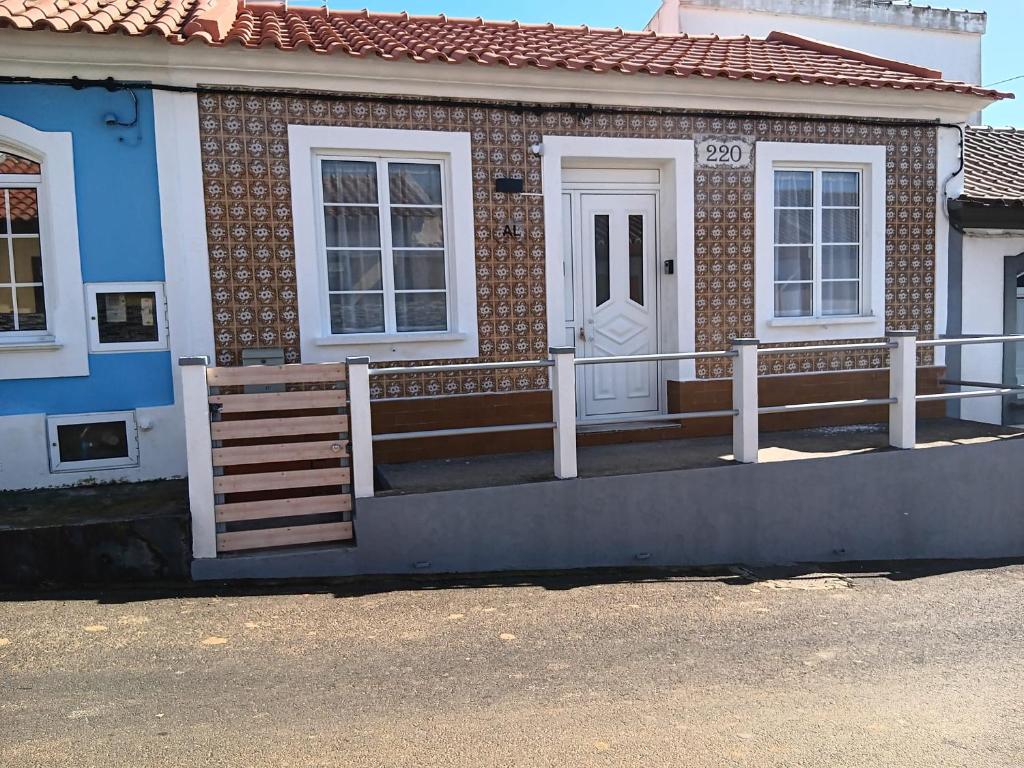 a brick house with a porch and a white door at Raiz Atlântica in Angra do Heroísmo