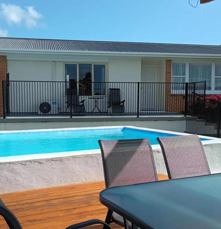 a swimming pool with chairs and a table and a table and a tablektop at B&B on Station in Paeroa