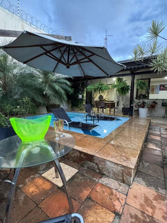 a patio with a table and an umbrella and a pool at Excelente Casa para 10 pessoas proximo ao Shopping Flamboyant- Serra Dourada-Autódromo in Goiânia