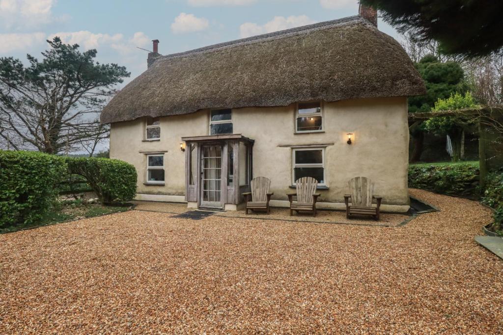 a cottage with two chairs and a thatched roof at Plenteth in Truro