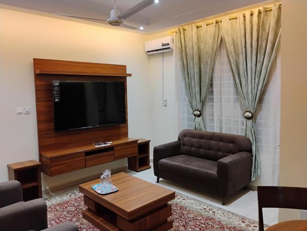 a living room with a couch and a flat screen tv at Chateau de Mankosah in Accra