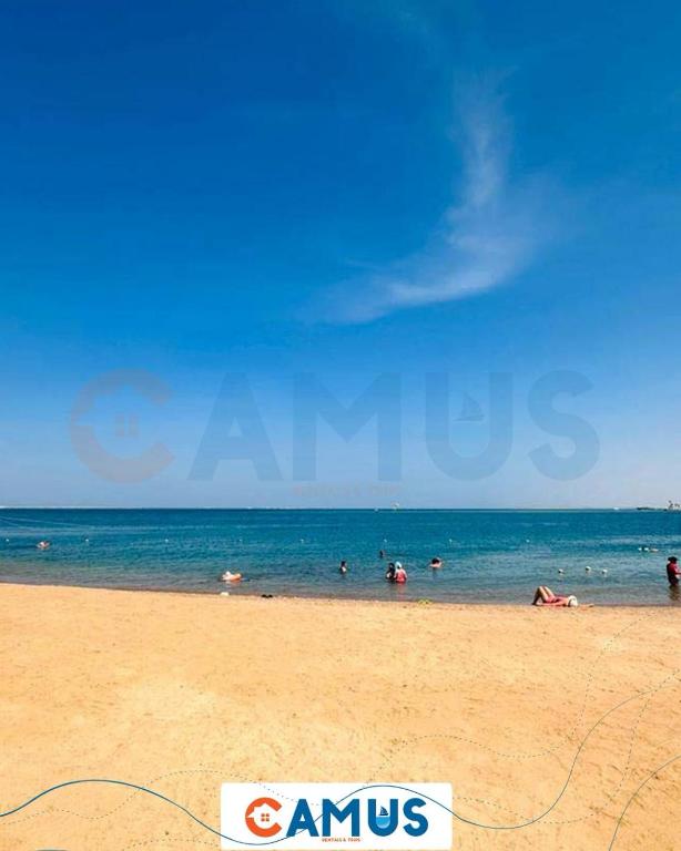 a beach with people swimming in the ocean at CAMUS 443, Princess Resort in Hurghada