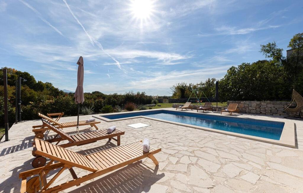 a swimming pool with two wooden chairs next to a pool at Old Oak Villa-house with Private Pool, Authentic Tavern & BBQ in Hrvace