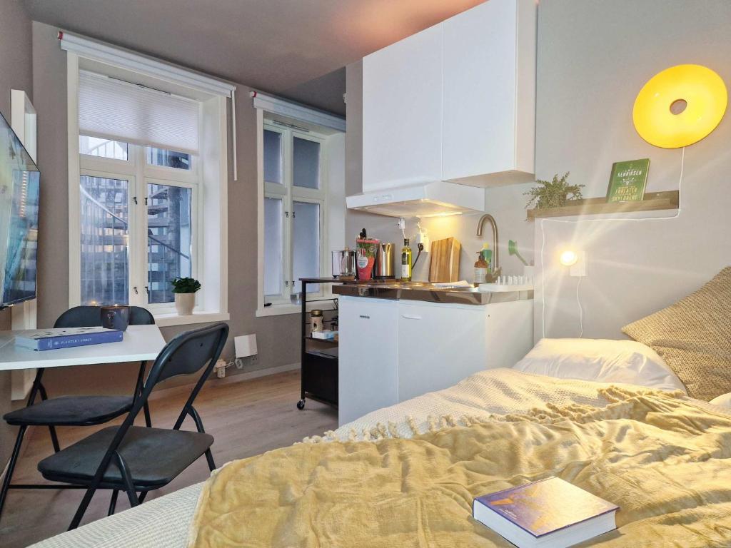 a bedroom with a bed and a desk and a kitchen at Cozy Central Studio by the Bus Station in Bergen