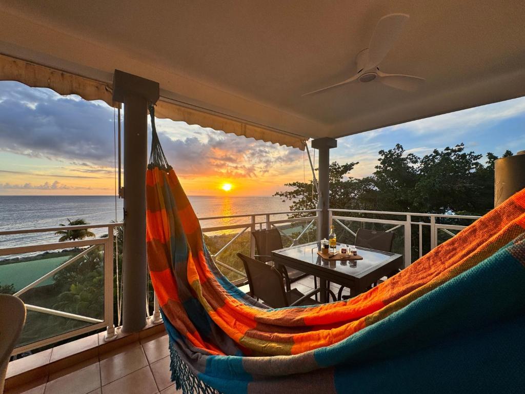 a hammock on a balcony with a view of the ocean at Horizon Doré Appt avec piscine - vue sur mer in Gourbeyre