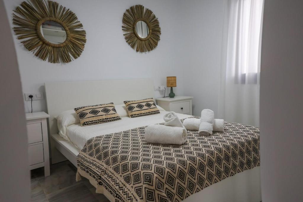 a bedroom with a bed with two pillows and a mirror at Charming Apartment with Private Terrace in Sanlúcar de Barrameda