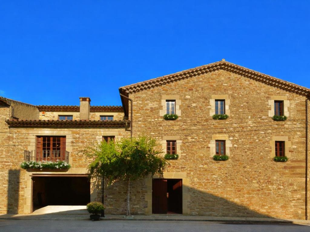 a large brick building with two garages at Masia Can Cenç in Collsuspina