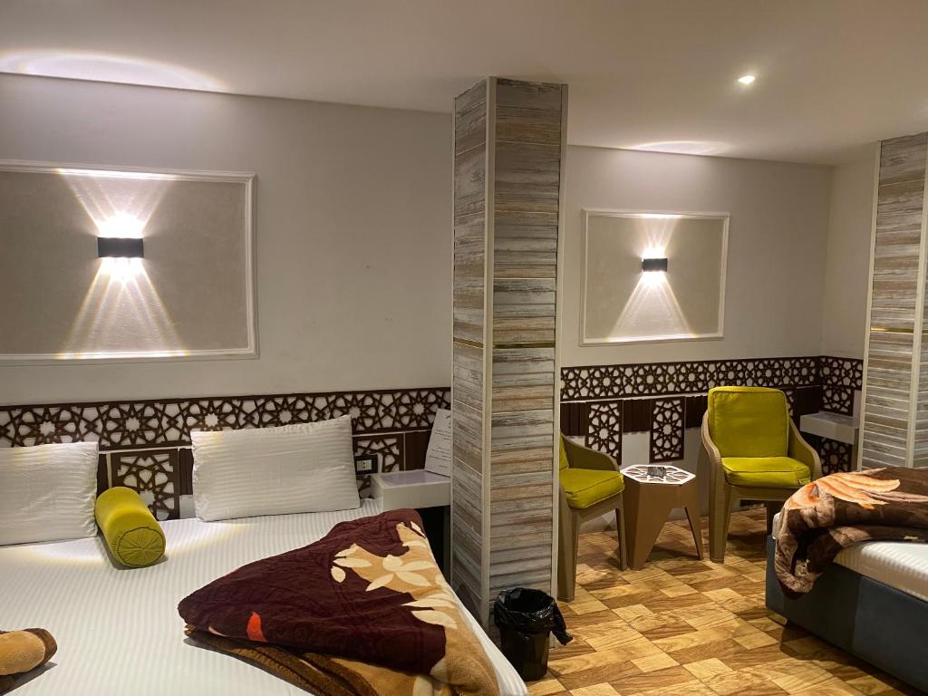 a bedroom with two beds and a yellow chair at Shaheen hotel in Suez