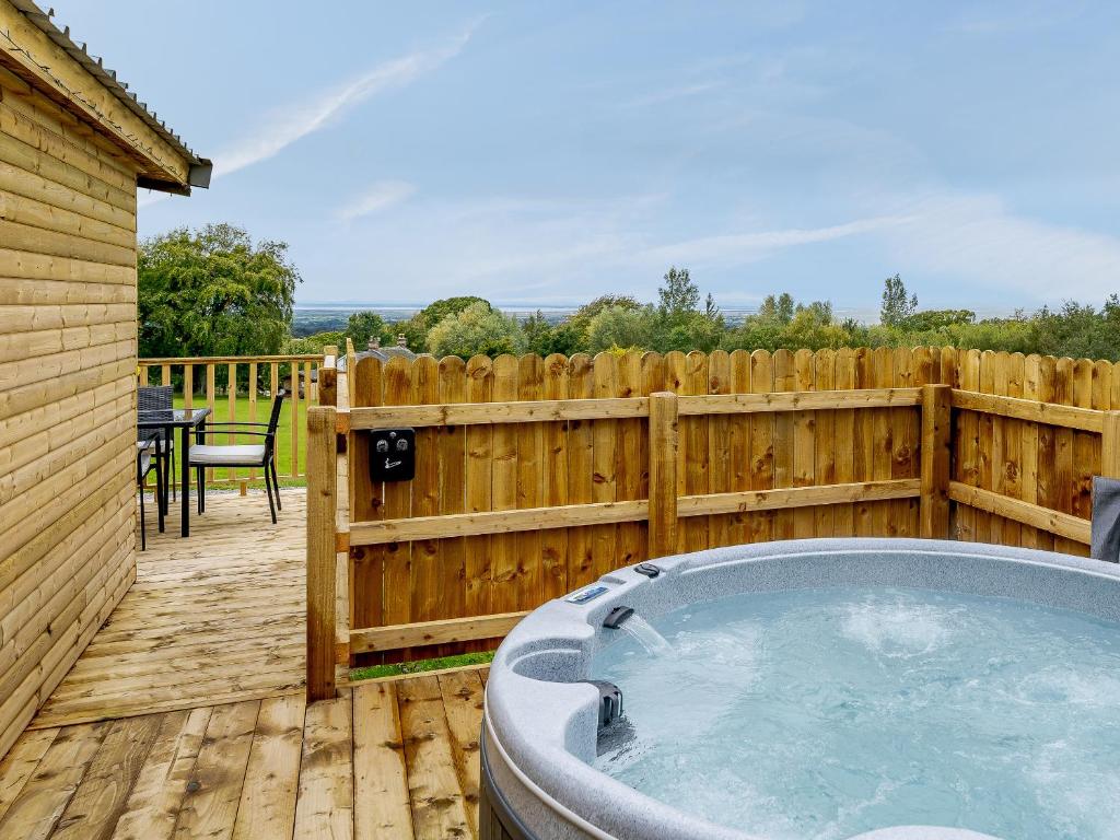 a hot tub on a wooden deck with a fence at Starling Lodge - Uk31071 in Westward
