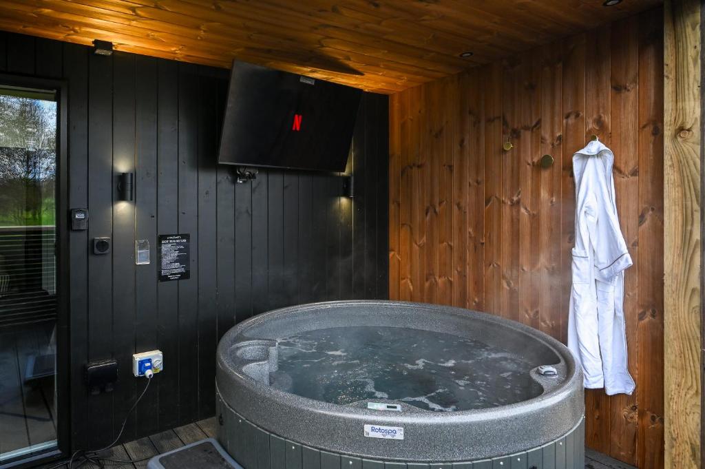 a bath tub in a wooden room with a white robe at Staining Luxury Lodges in Poulton le Fylde